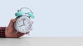 Retro styled white alarm clock in manÃ¢â¬â¢s hand, isolated, blue